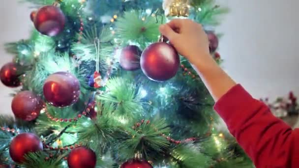 Feliz bebê mão pendurada bola em uma árvore de Natal, crianças decorando uma árvore de Natal. — Vídeo de Stock