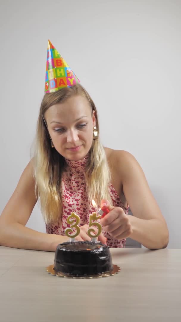Egy nő gyertyát gyújt a születésnapjára. függőleges videó — Stock videók