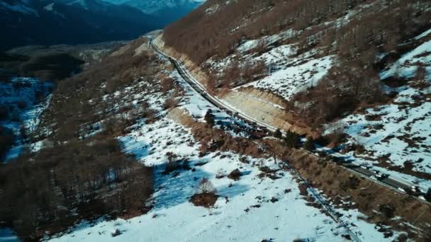 Flyg med flyg i vinterlandskapet. bilar som kör på vintern på en snöig väg mellan bergen. Italien bergstur, Ambruzzo. visa drönare. — Stockvideo
