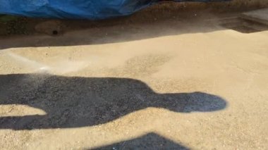 Bir işçi, basınç altında betondan kiremitleri suyla yıkar..