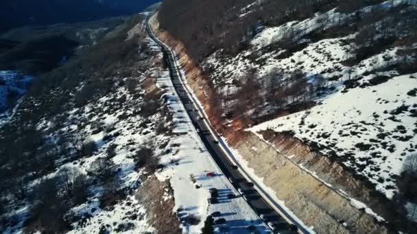 Vol aérien dans le paysage hivernal. voitures conduisant en hiver sur une route enneigée entre les montagnes. Voyage en montagne en Italie, Ambruzzes. vue drone. — Video