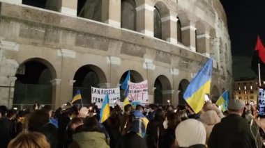 Roma, İtalya - 25 Şubat 2022 Ukrayna 'nın işgaline karşı savaş karşıtı protesto ya da miting. Göstericiler gece Ukrayna bayrakları ve posterleri sallıyor. Kalabalık toplanıyor. Geniş 4K panoramik çekim
