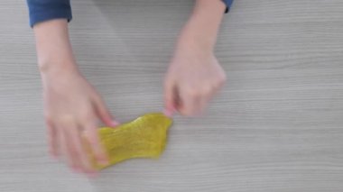 Yapışkan maddeyi germek için baloncuklarla el sıkışmak. Genç el yeşil, parlak balçık tutuyor, sıkıyor. Yanlara balçık oyuncağı serpiştiriyorum. Sıvı oyuncak.