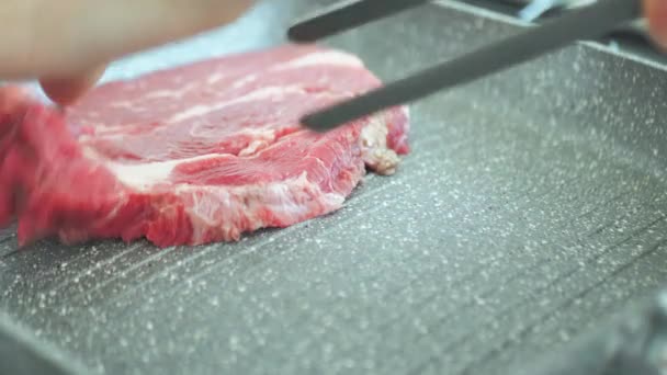 Kapcsolja be a marhahús steak a serpenyőben fogóval. — Stock videók
