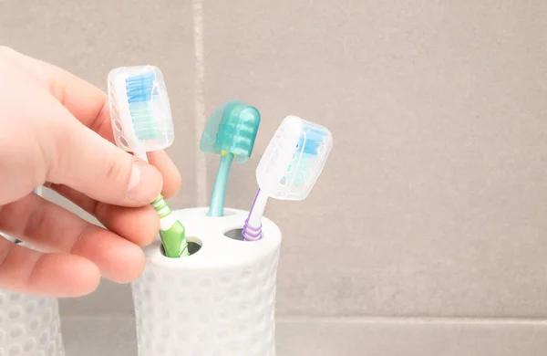 The man pulls a toothbrush from the holder. Hand on the left side of the frame — Stock Photo, Image