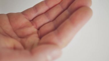 İki beyaz hap şişeden avuç içine düştü. Yakın plan.