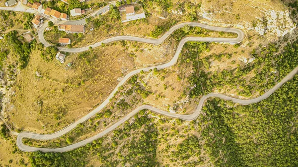 Vířící pohled na silnici z leteckého pohledu. Na vrchol města stoupá klikatá cesta — Stock fotografie