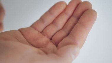 İki beyaz hap şişeden avuç içine düştü. Yakın plan.