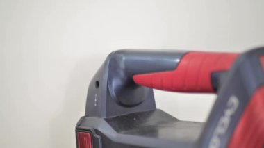 Adam şarj aletinin fişini elektrikli süpürgeye takıyor..
