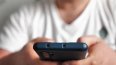 Genç adam cep telefonuna bak ve sosyal ağlara yakından bak. Sohbet odasında cep telefonuna dokun. Cep telefonunda yaşam