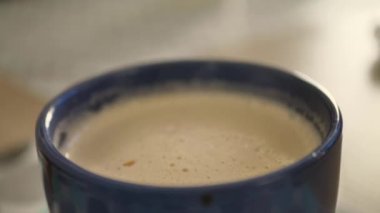 Kahve kapuçinosuna kruvasan batır. Erkek eller taze Fransız kruvasanını süt köpüklü kapuçino, ahşap masa arkaplanlı bir fincan kahveye batırıyor.