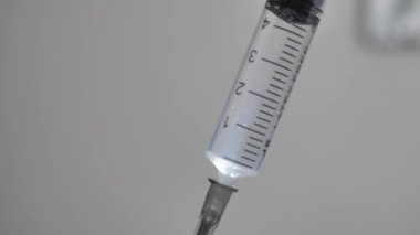 Beyaz bir zemin üzerinde insan elinde bir enjeksiyon şırıngası üzerine seçici bir odak.