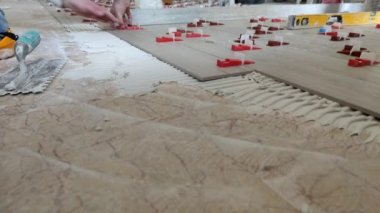 Seramik zemin fayansları yerleştiriliyor, fayansları yapıştırıcı malzeme yatak içine yerleştiriliyor.