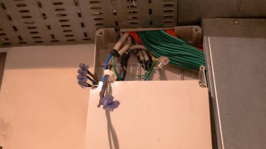 Duvarda kablolar olan kutular. Kablo arka plan. Beton duvardaki elektrik prizlerinden sarkan renkli elektrik kabloları. Yeni elektrik kablosu kurulumu.