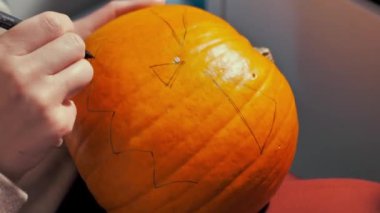 Hands carves a scary halloween pumpkin. Making pumpkin decor for Halloween. Preparation for celebration. Preparing halloween pumpkin, Jack-O-Lantern