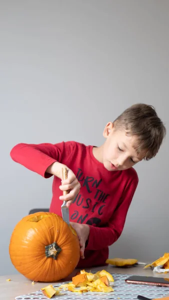 Boy busy carving a pumpkin jack-o-lantern for Halloween - removing the seeds.
