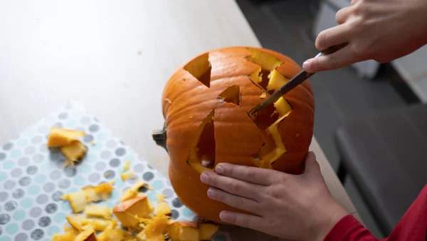 Boy busy carving a pumpkin jack-o-lantern for Halloween - removing the seeds.