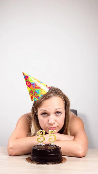 Bored Blonde Celebrating Her Birthday While Sitting Birthday Cake Table — Stockfoto