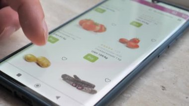 Akıllı telefon kullanan bir adam çevrimiçi bir mağazadan satın alır. Bir adam online markette sebze seçiyor..