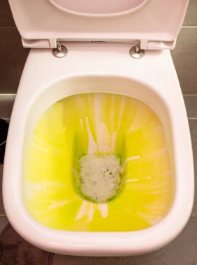 Cleaning and disinfection concept. White toilet with green detergent after flushing