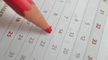 Wall calendar, the number of the month is crossed out. A hand crosses out the days on a paper calendar with a red pen. A very important date in the calendar. Signing the day in the calendar