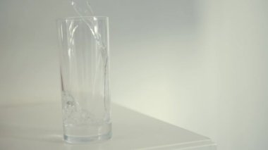 stüdyo çekimi şeffaf cam içine beyaz zemin üzerine dökülen su