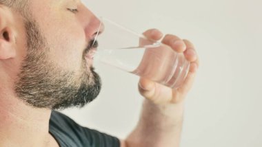 Genç bir adam bir bardaktan su içer.