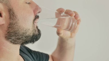 Genç bir adam bir bardaktan su içer.