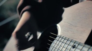 A guitarist plays a classical wooden guitar. A musician plays the guitar near a tent on the street, Up close