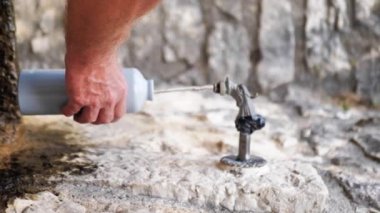 a person bottles water from a street faucet, vertical video