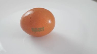 a mans hand takes a chicken egg from a white plate, close up