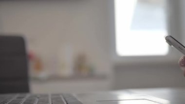 businesswoman sitting in modern office texting on smartphone, sharing success messages on social media. Attractive happy business freelancer reading good news on the phone