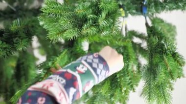 the boy spreads the branches of the Christmas tree. vertical video.