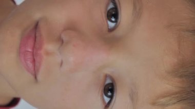 scratching his nose with a finger with the symptom of atopic dermatitis on the nose and white background. the skin on the nose is scaly. vertical video