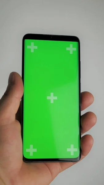 Hand holding smartphone isolated on green background., The shape of a modern mobile smartphone Designed to have a thin edge. green screen background - Clipping Path.
