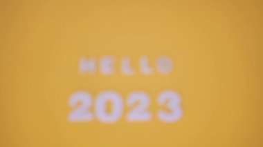 Merhaba 2023 ahşap bloklarda bulanık park geçmişi olan metin. Sarı arka planda. Yeni yıl kavramı