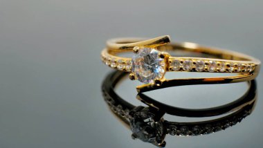 Yansıyan siyah masada elmas takılı altın bir yüzük..