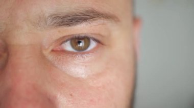Close-up of a mans face. Caucasian young male model with blue, green, gray eyes looking at camera. Slow motion, extreme macro close-up, 4K