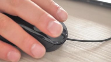 Close-up of a mans hand using a black mouse. Close-up of a mans hand scrolling the wheel of a light mouse. The guy presses the buttons of a stylish mouse with his hand close-up. The camera falls