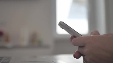 at workplace using smartphone, texting, choose and buy goods and services online, concept of using modern technology. Close-up of female hands holding mobile phone sitting at table.