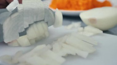 Adam mutfakta soğan doğruyor. Erkek elleri soğanları bıçakla kesiyor. Kapat.