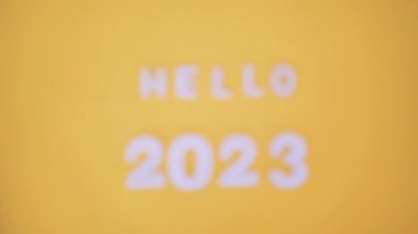 Merhaba 2023 ahşap bloklarda bulanık park geçmişi olan metin. Sarı arka planda. Yeni yıl kavramı