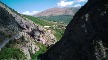 Flying drone over mountains with winding mountain road and forest. Italy Abruzzo. a drone flies over a beautiful landscape, cars move on a dangerous road