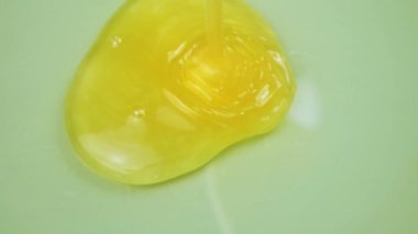 Yavaş çekimde sıvı sarı altın renginde jel dökülüyor. Krem jöle, köpüklü kozmetik doku. Makro çekim.