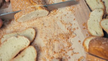 Tahta bir yüzeye susam tohumlu dilimlenmiş Fransız ekmeği ekmeği..