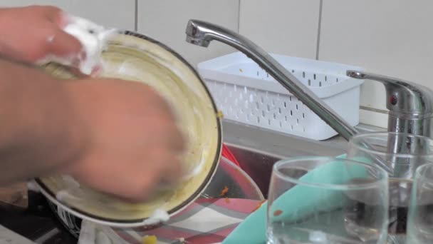 Молодой Человек Моет Дома Посуду Мылом Губкой Тщательно Протирает Тарелку — стоковое видео