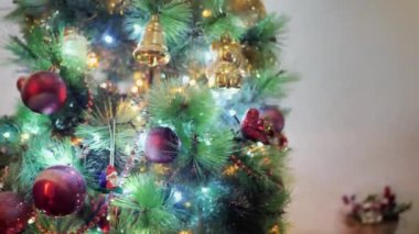 Çocuklar Noel 'i veya Yeni Yıl Ağacı' nı kürenin oyuncaklarıyla süslüyor. Bebek nazikçe kırmızı topu düzeltir. Küçük çocuk Noel süslerini Noel süslemelerine asıyor.