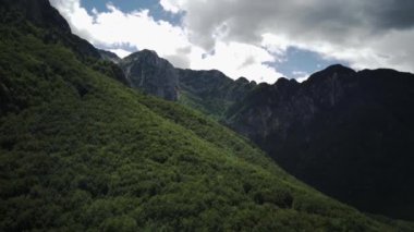 Aerial view around a bare valley amidst mountains and foliage in sunny Abruzzo, Italy circling drone shot
