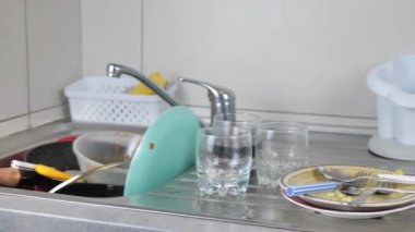 Yemek artıklarıyla dolu kirli tabaklarla dolu metal lavabo. İhmal edilmiş renkli kase ve kap kacak yığınları. Dağınık bir mutfakta yemek pişirmenin sonucu. Kamera hareketiyle 4K videosunu kapat