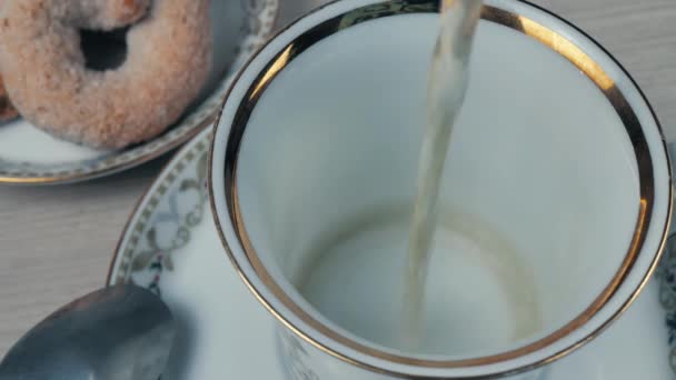 カップに緑茶を入れてください 円盤に金色の縁を持つ白いマグカップ — ストック動画